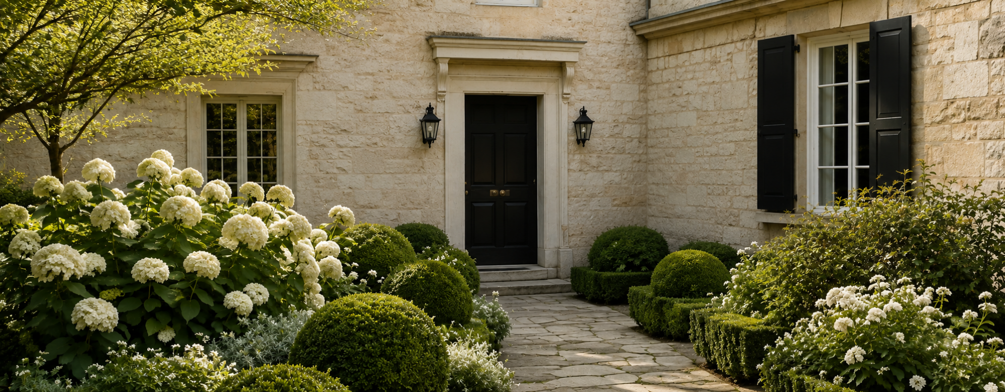 European limestone facade surrounded by white hydrangeas and evergreen structure